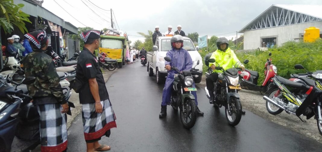 Meski Ditemani Hujan, Babinsa Satra Tetap Semangat Beri Pengawalan Ngiring Ida Ratu Gede Dan Sanghyang Tri Durga Tedun Ke Desa Adat Tanggahan Peken