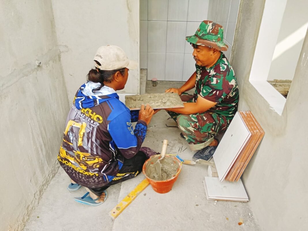 Satgas TMMD Kodim 0813 Lanjutkan Pemasangan Keramik di Musala dan MCK
